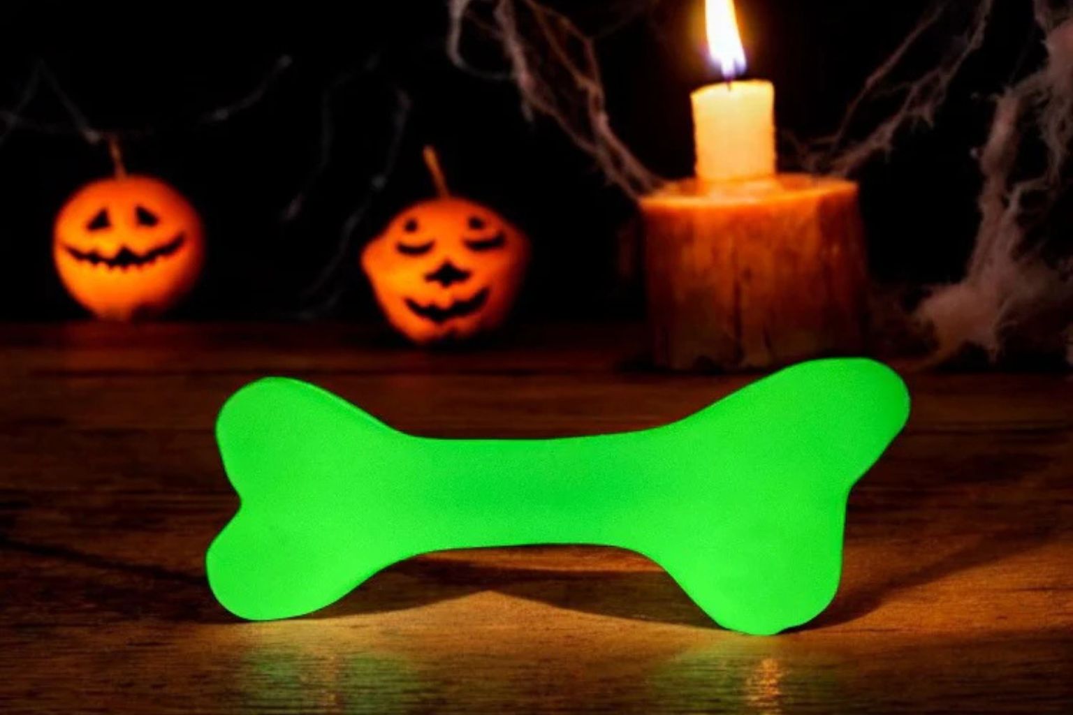 Glow in the dark dog bone treat dispenser with halloween candles in the background